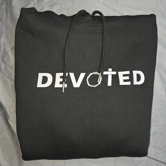 Black hoodie with 'DEVOTED' printed on it, folded on a gray surface